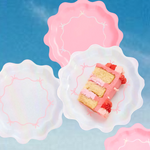 Slice of cake with pink and red frosting on a decorative plate against a blue background