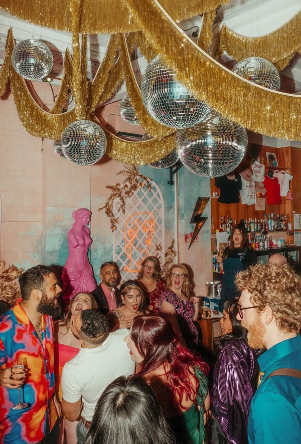 People socializing in a room with disco balls and a chandelier